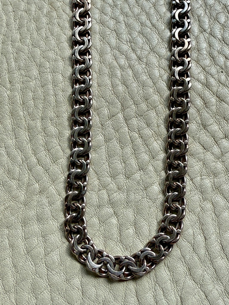 Silver chain necklace on a textured light gray surface
