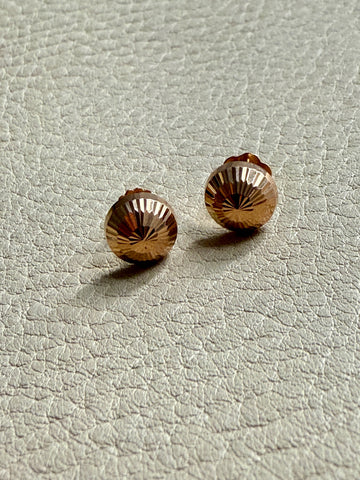 Pair of gold stud earrings on a light gray textured surface