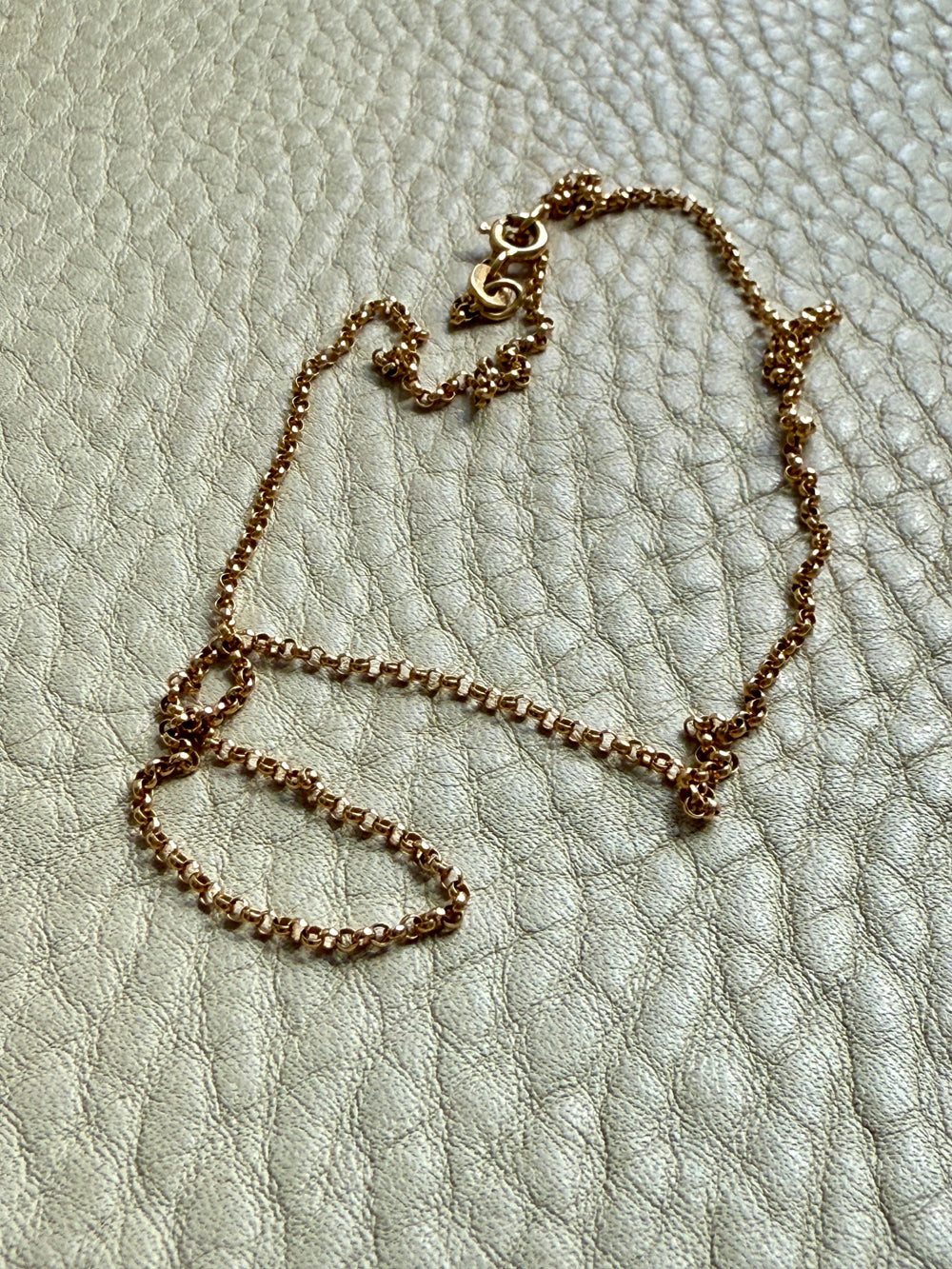 Gold chain necklace on a textured light gray surface