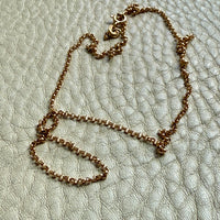 Gold chain necklace on a textured light gray surface