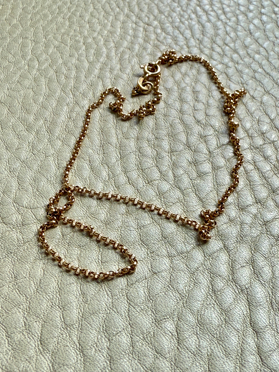 Gold chain necklace on a textured light gray surface