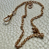 antique 18k Gold watch chain with dog clip on a textured light gray background