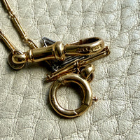 Gold necklace with a clasp on a textured beige background