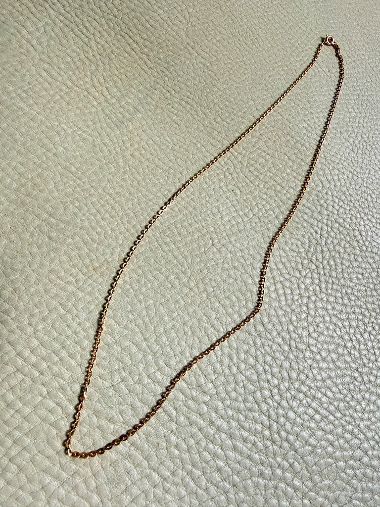 Gold chain on a textured beige surface