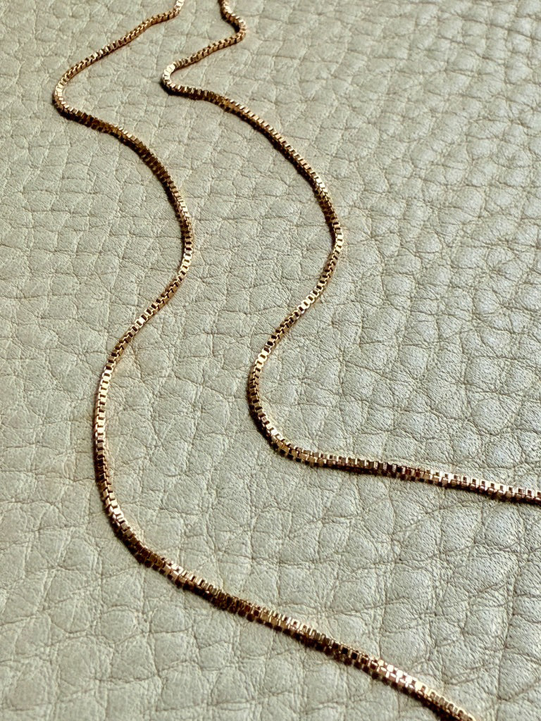 vintage 18k gold chain necklace on a textured light green surface