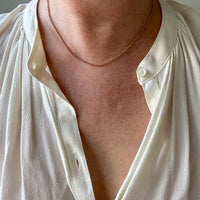 Close-up of a person wearing a white shirt with a necklace.