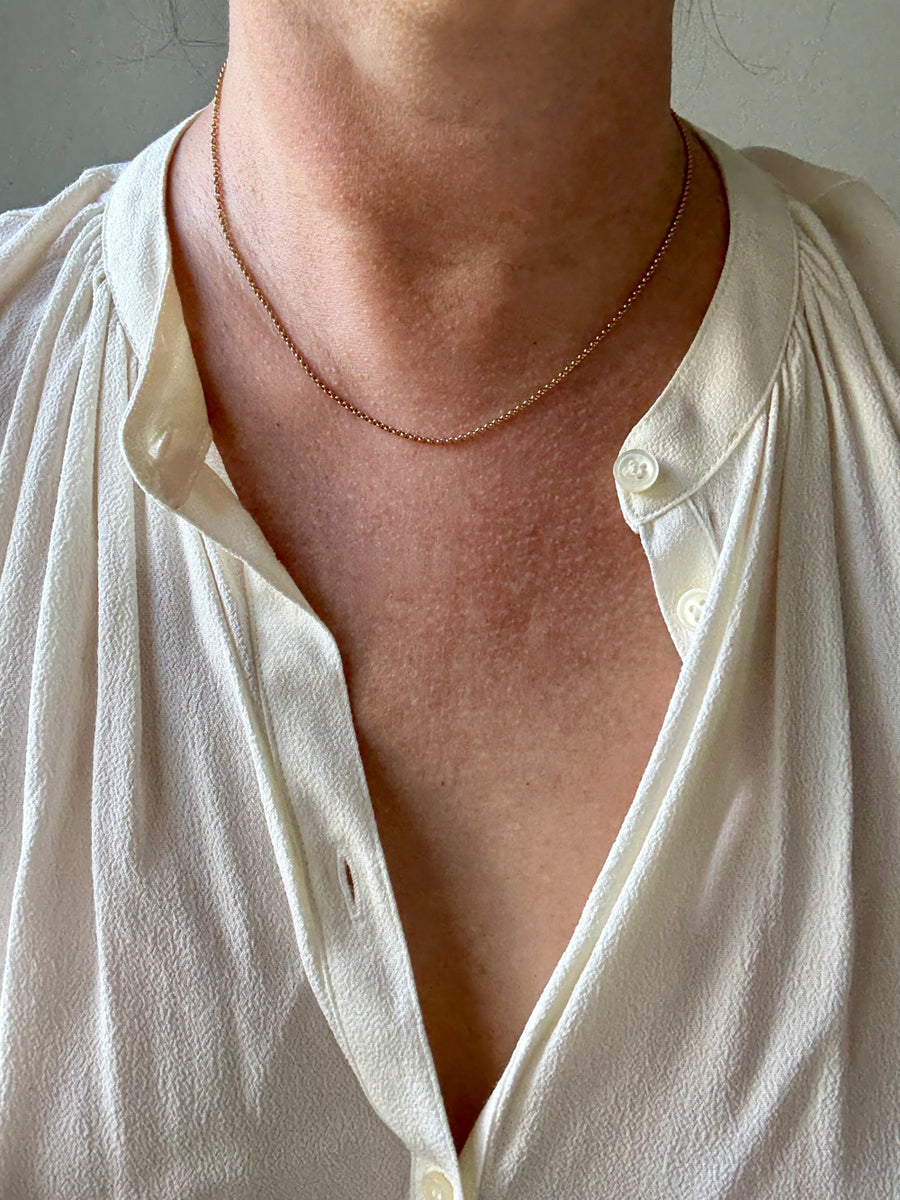Close-up of a person wearing a white shirt with a necklace.