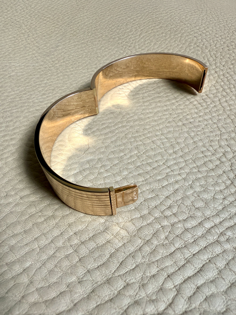 Gold bracelet on a textured beige surface
