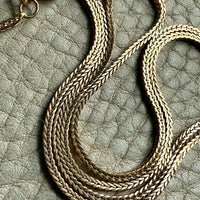Vintage Italian 18k Gold wheat link necklace on a textured gray surface PenelopePenelope.com