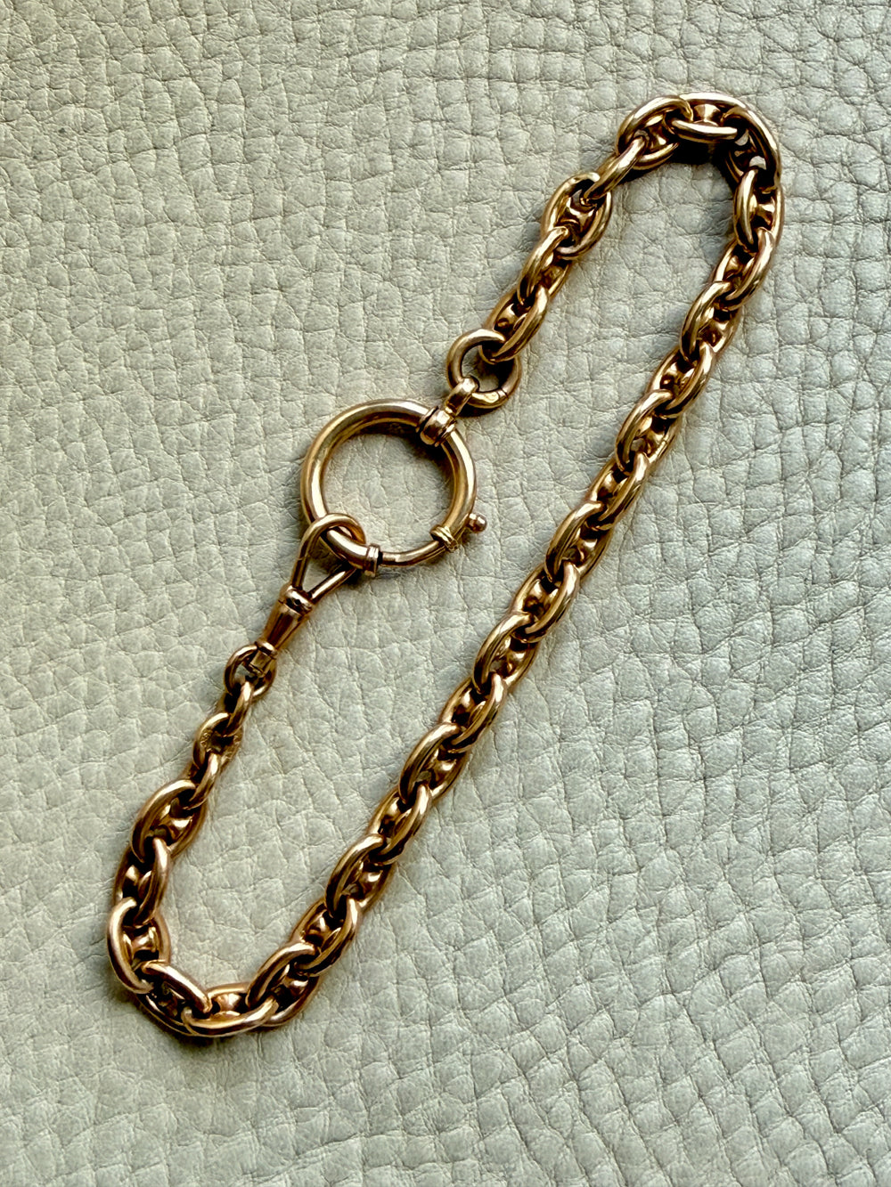18k gold antique watch chain bracelet on a light green textured surface