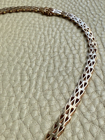 gold chain necklace on a textured beige surface