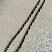 Necklace with silver beads on a textured beige surface
