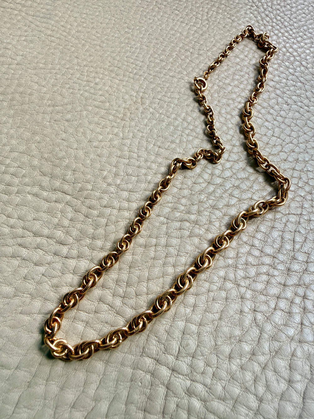 Gold chain necklace on a textured light gray surface