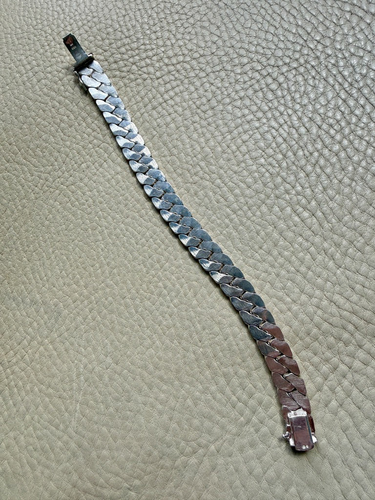 silver chain bracelet on a textured beige surface