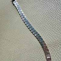 silver chain bracelet on a textured beige surface