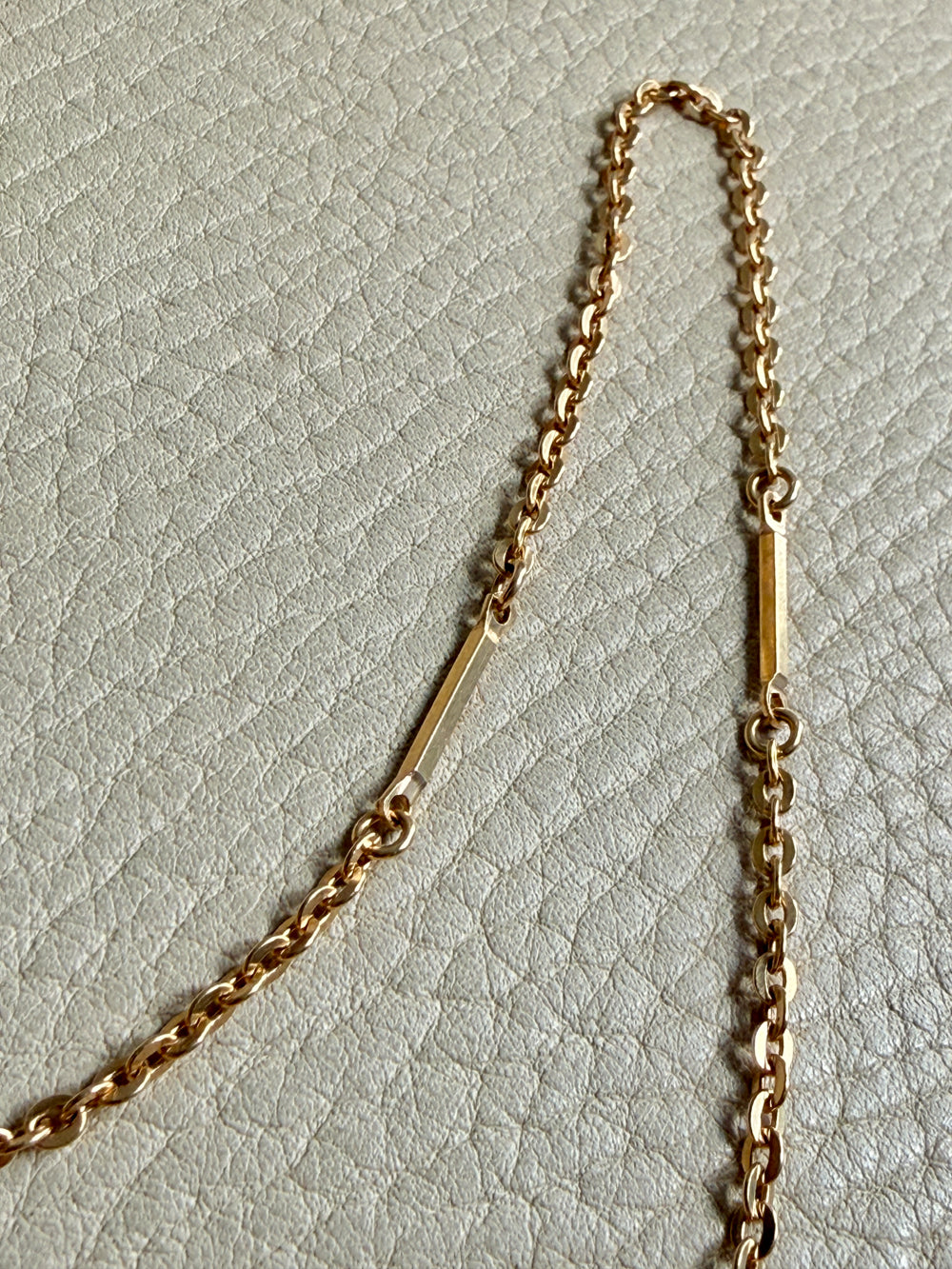 Gold chain necklace on a light gray textured background