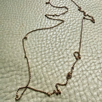 18k gold curb link Necklace on a textured light green surface