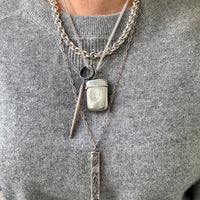 Person wearing a gray sweater with layered silver necklaces