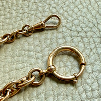 Gold mariner link chain with clasp on a textured light green background