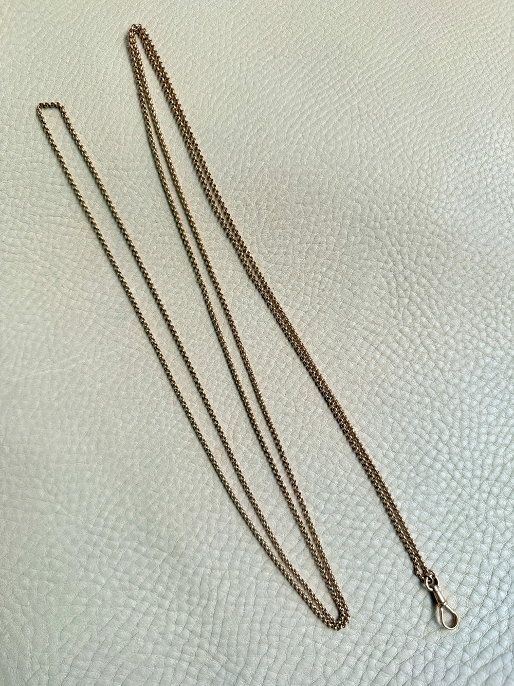 Gold chain necklace on a textured white surface