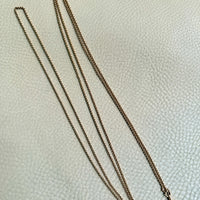 Gold chain necklace on a textured white surface