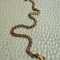 Gold chain bracelet on a textured light green surface