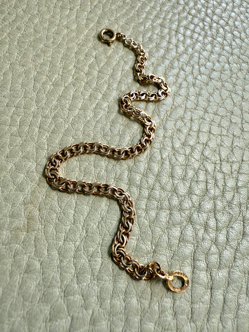 Gold chain bracelet on a textured light green surface