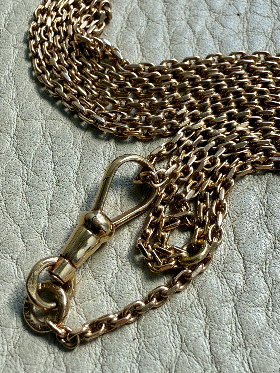 18k Gold chain necklace with dog clip on a textured surface