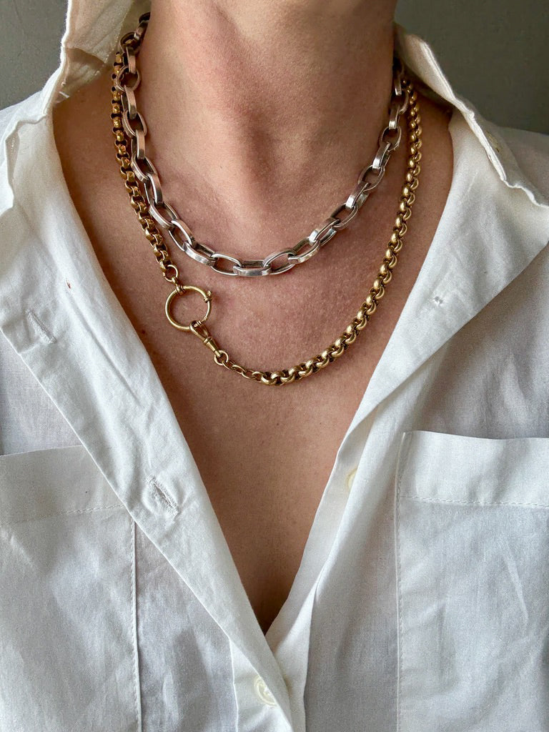 Necklace with gold and silver chains worn by a person in a white shirt.