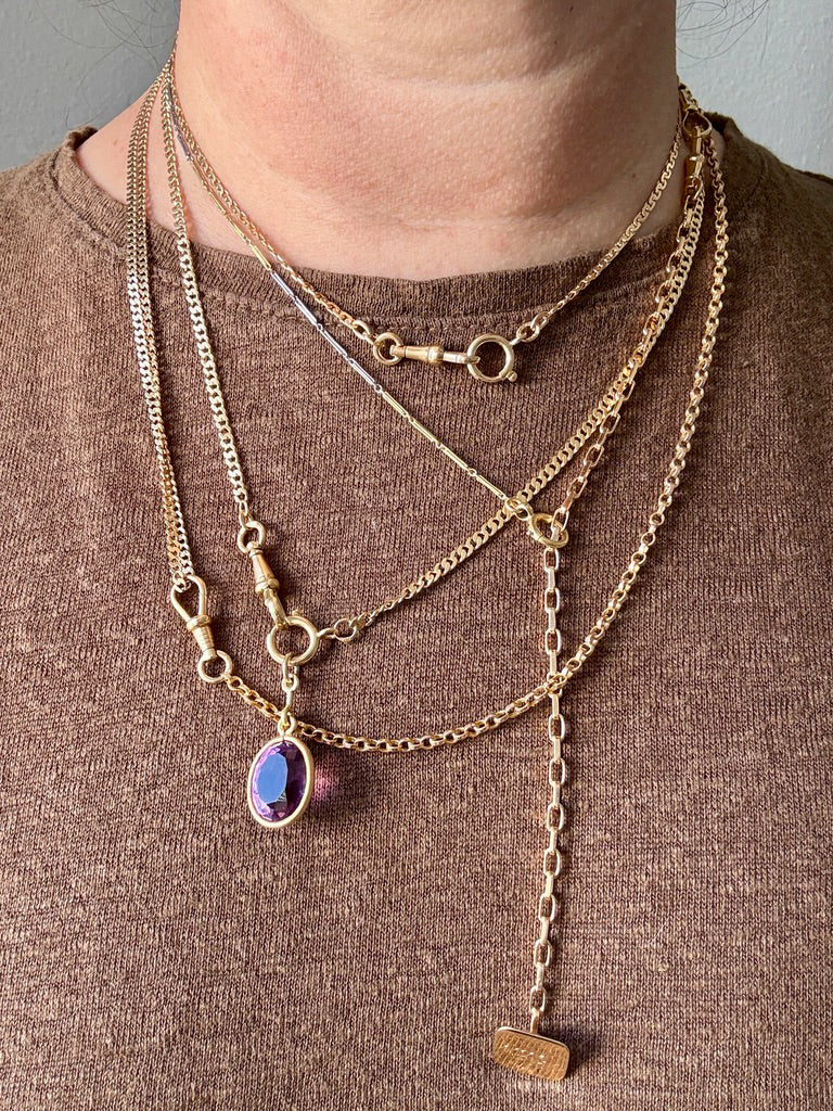 Person wearing multiple gold necklaces with a brown background