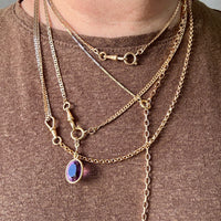 Person wearing multiple gold necklaces with a brown background
