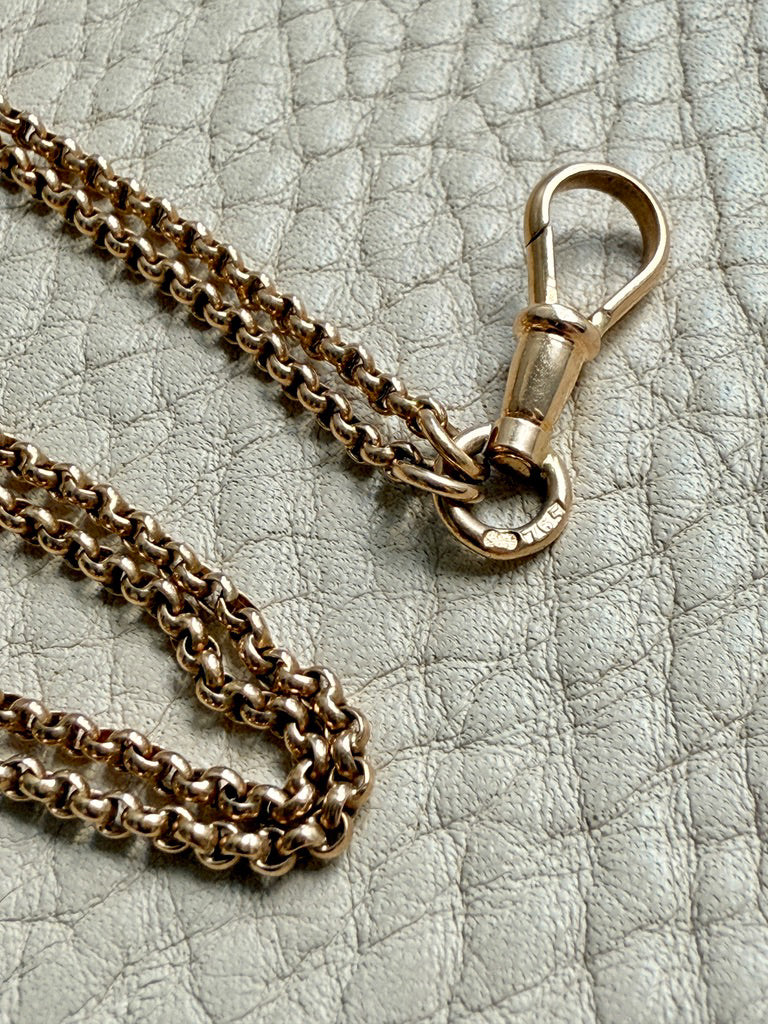 Gold chain necklace with clasp on a textured gray surface