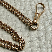Gold chain necklace with clasp on a textured gray surface