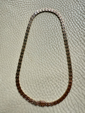 gold chain necklace on a textured light gray background