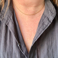 Person wearing a gray shirt with a gold necklace