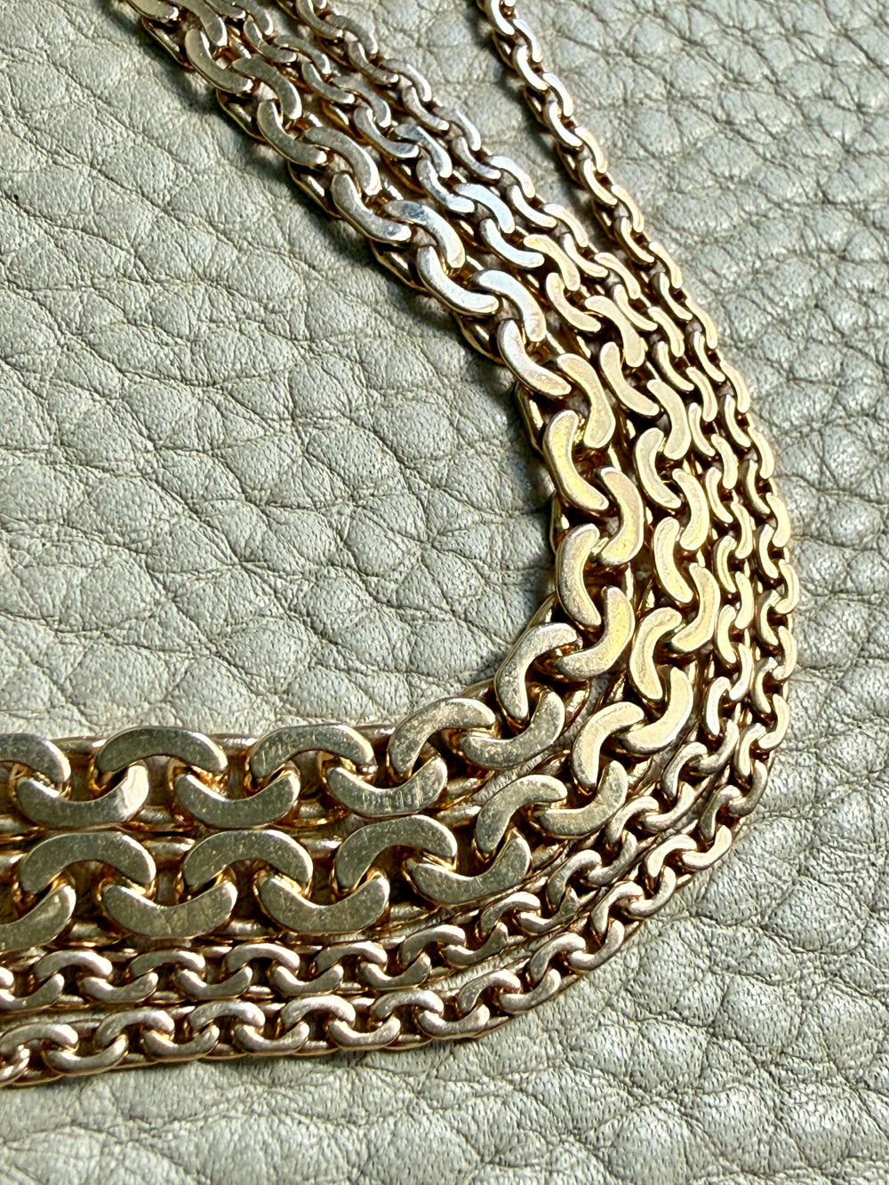 Gold chain necklace on a textured light gray surface