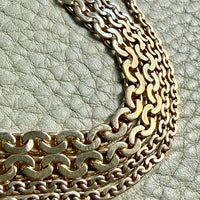 Gold chain necklace on a textured light gray surface