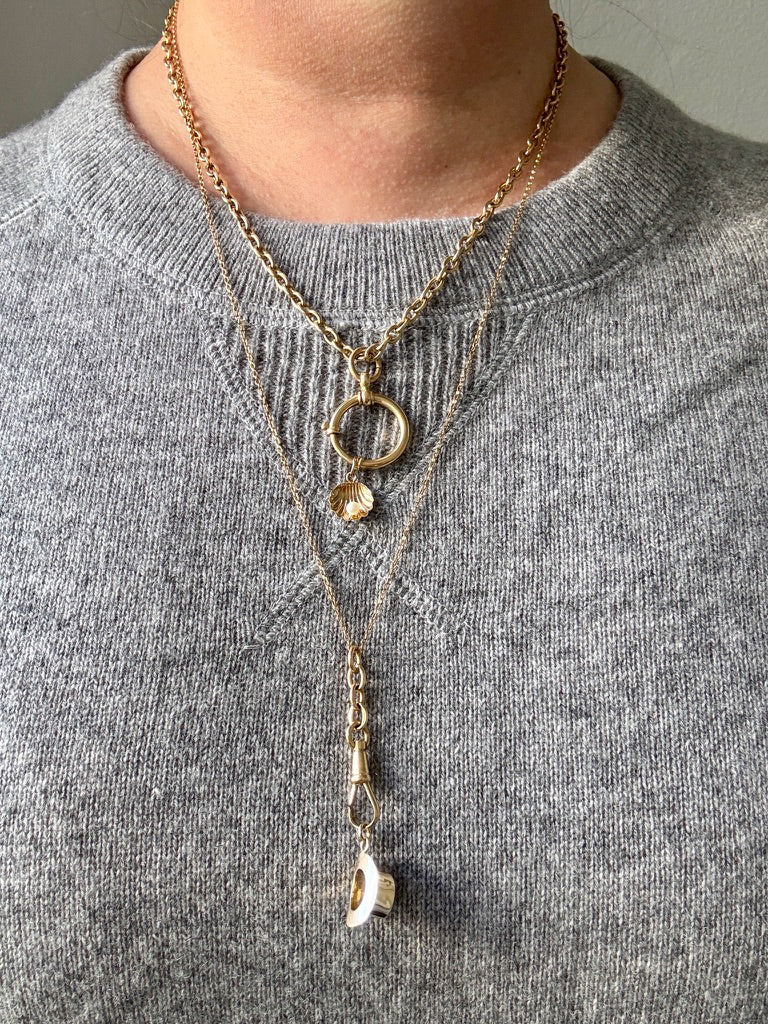 Gold necklace with pendant on a gray sweater
