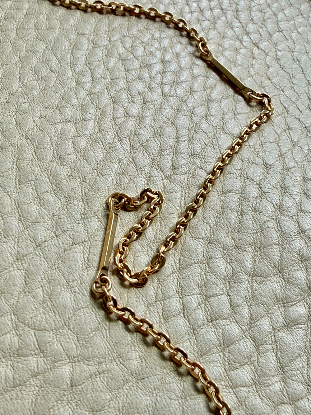 Gold chain necklace on a textured light gray surface