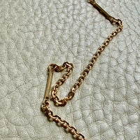 Gold chain necklace on a textured light gray surface