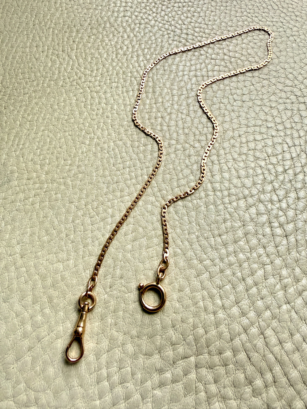 18k Gold virola link watch chain on a textured light gray surface