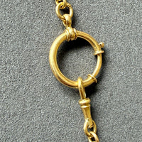 Gold necklace with a unique clasp design on a gray background
