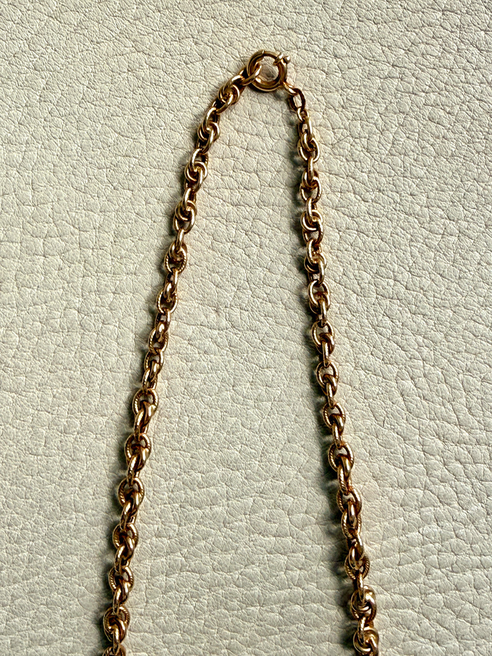 Gold chain necklace on a textured light gray background