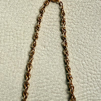Gold chain necklace on a textured light gray background