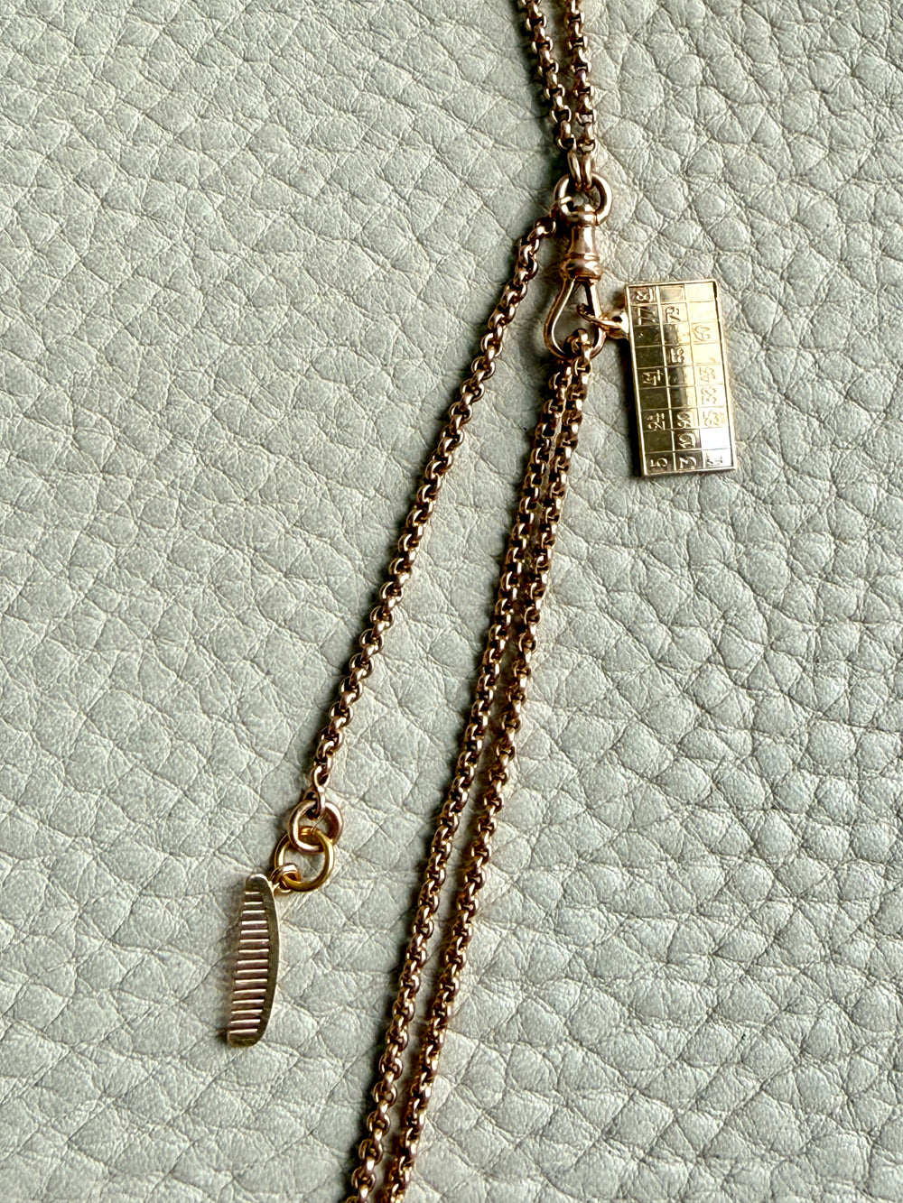 Gold necklace with a tag on a textured light green background
