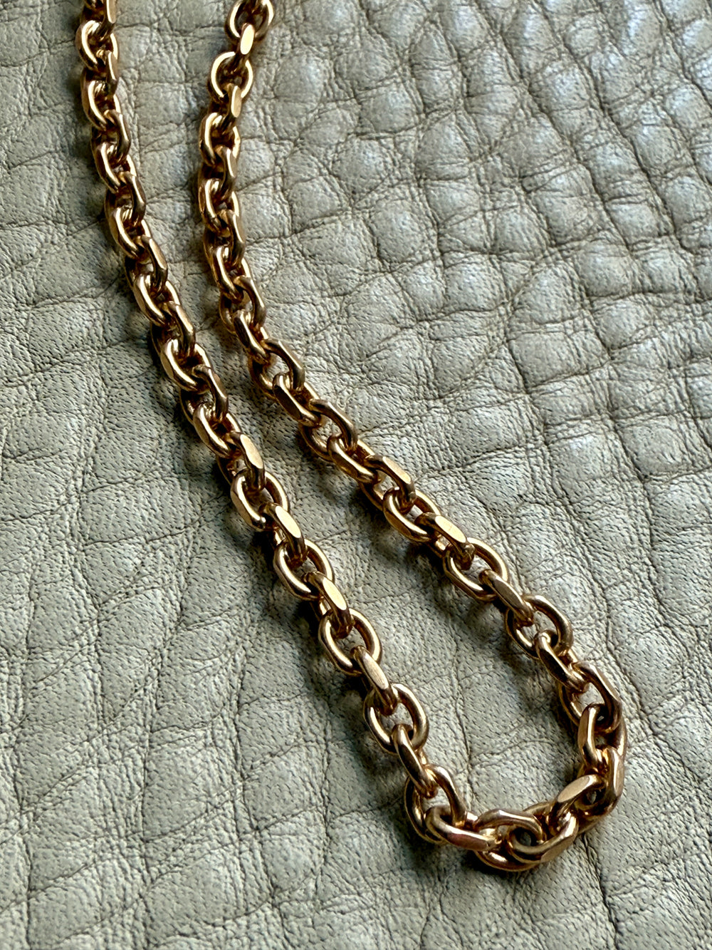 Gold chain necklace on a textured light gray surface