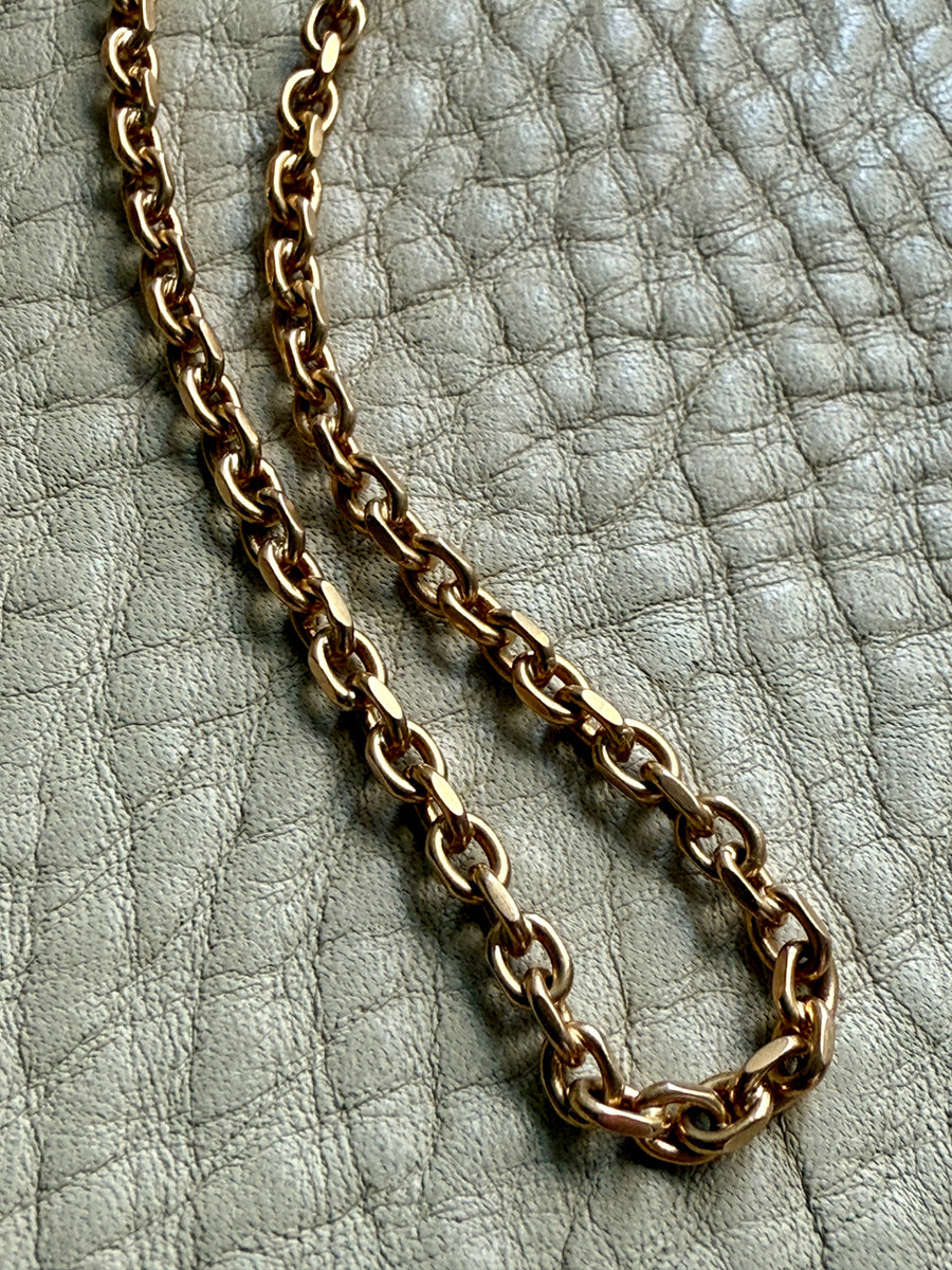 Gold chain necklace on a textured light gray surface