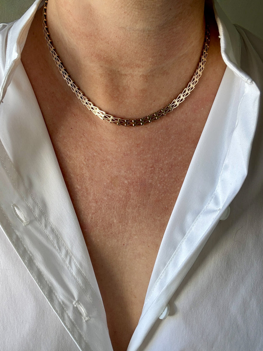 gold chain necklace worn by a person with a white shirt.