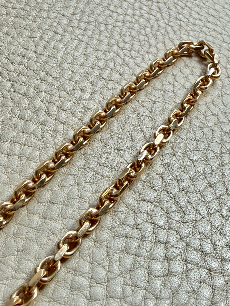 18k Gold chain biker link on a textured light gray background