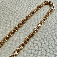 18k Gold chain biker link on a textured light gray background